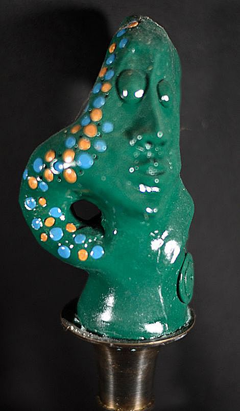 Green  polymer clay sculputre of figure with hand resting on waist iwth decorated sleeve in blue and orange by artist Hollis Richardson 