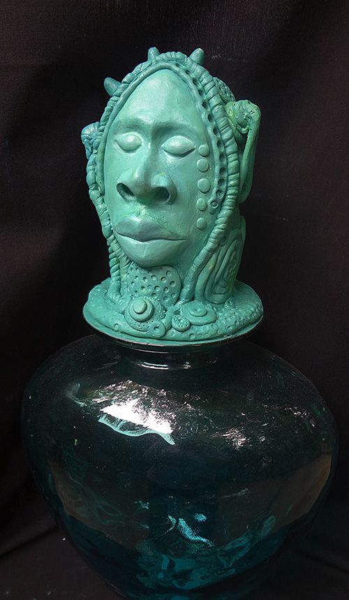 Green polymer clay sculpture of face with wide nose, large lips and hair  and decor in coils by artist Hollis Richardson 